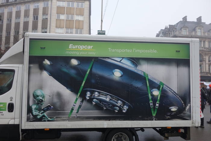 Transport d'ovni? — Flanc publicitaire d'un utilitaire Europcar dans une rue de Bruxelles — Bruxelles