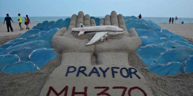 Des promeneurs passent sur une plage à Puri en Inde où l'artiste Sudersan Pattnaik a sculpté dans le sable   un mémorial aux victimes du vol MH370, le 12 mars 2014 