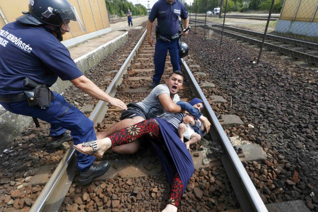 Migrants s'accrochant à des rails