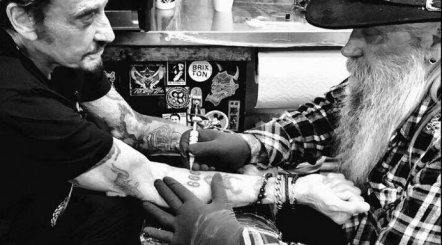 Johnny Hallyday en train de se faire tatouer le nombre 666 sur son avant-bras droit en 2014