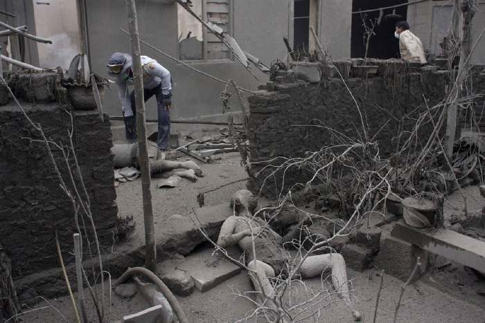 Des volontaires recherchent des survivants   au milieu des cadavres de victimes brûlées par les retombées de cendres à Argomulyo