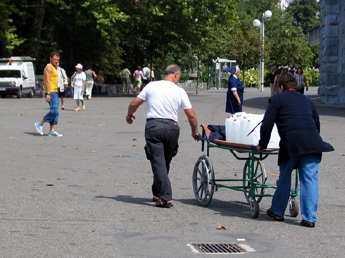 Transport de bidons d'eau sur le site des sanstuaires à Lourdes